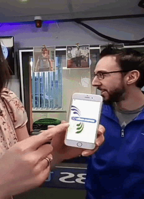 a man in a blue jacket is holding a phone with a dragonfly on it