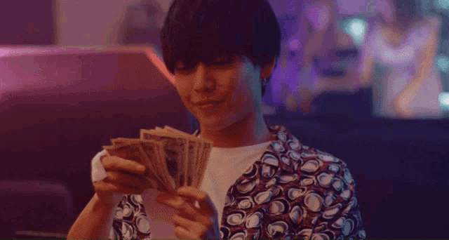 a man in a polka dot shirt is holding a bunch of money