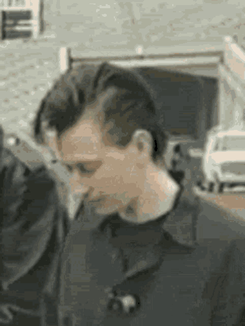 a man with a mohawk hairstyle is standing next to another man in front of a garage .