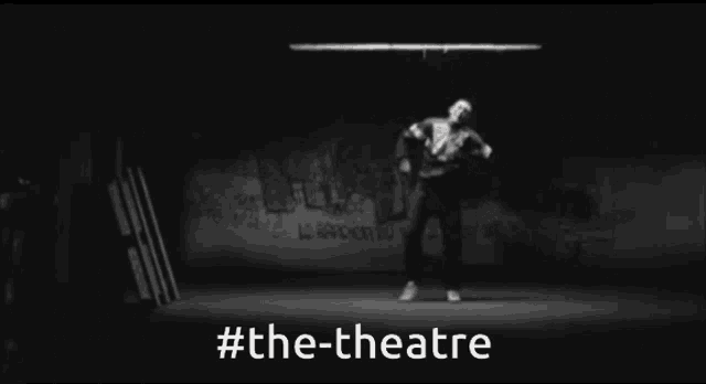 a black and white photo of a person jumping in the air with #the-theatre in white letters