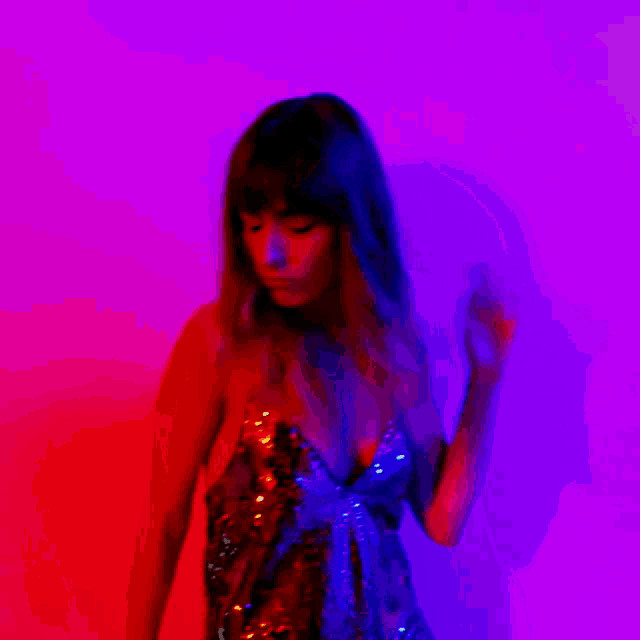 a woman in a sequined dress is dancing in front of a red and blue background .