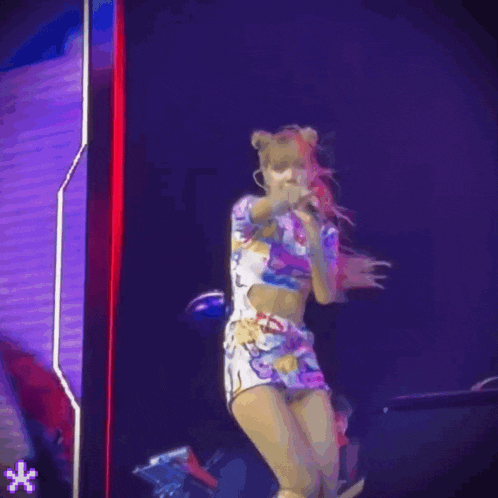 a woman in a hello kitty outfit is singing into a microphone on a stage .