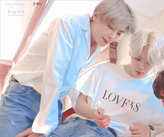 a man wearing a white shirt that says love 's is sitting next to another man