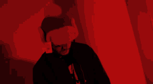 a man wearing a hat and ear muffs is standing in a red room