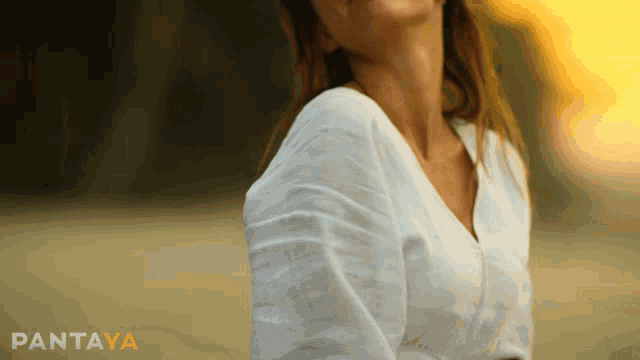 a woman in a white shirt is sitting in front of a pantaya logo