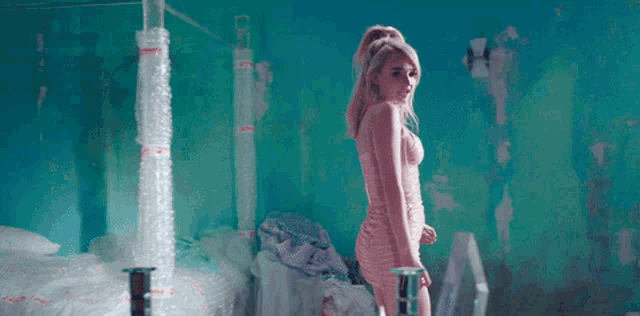 a woman in a pink dress is standing in a room with a blue wall