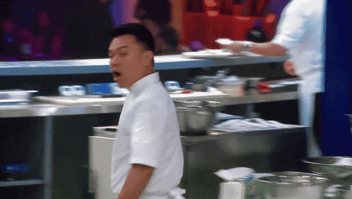 a man in a white shirt is standing in a kitchen