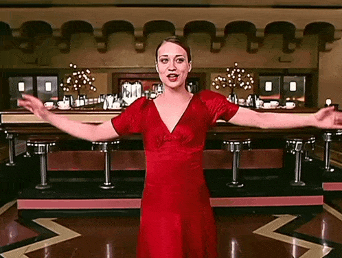 a woman in a red dress is standing in front of a diner