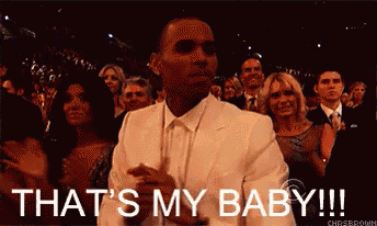 a man in a white suit stands in a crowd and says that 's my baby