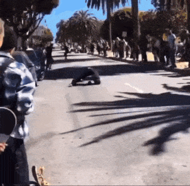 a person riding a skateboard down a street with palm trees