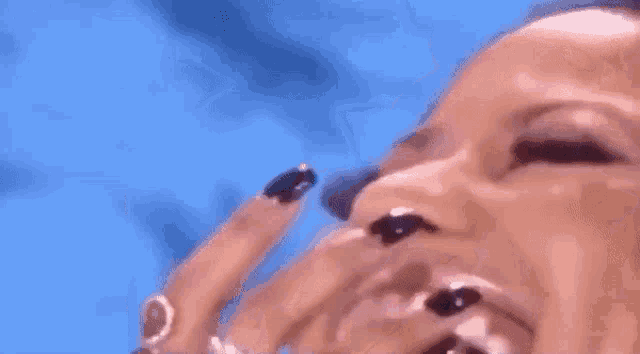 a close up of a woman 's face with a blue background and a woman 's teeth .