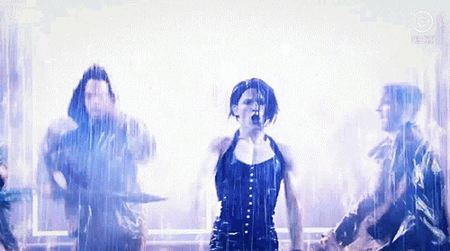 a woman in a black corset is screaming in the rain while a man plays drums