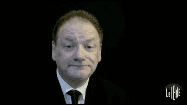 a man in a suit and tie is making a face on a black background .