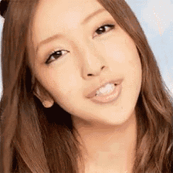 a close up of a woman 's face with long hair and a smile .