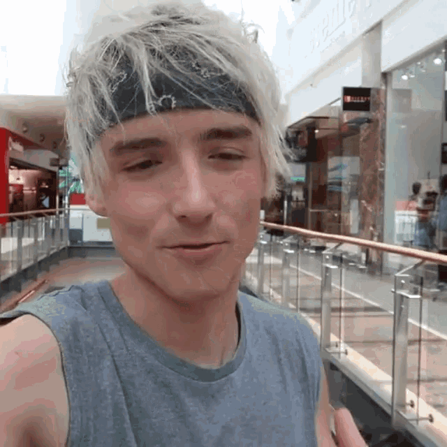 a young man wearing a headband and a gray tank top