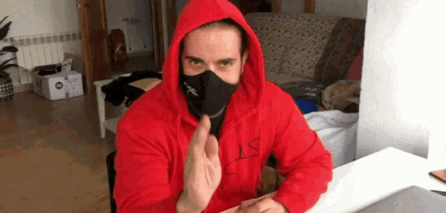 a man wearing a red hoodie and a black mask with the letter a on it