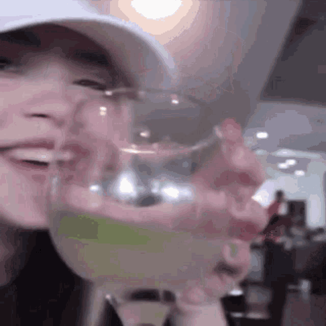 a woman wearing a white hat is holding a glass of liquid in her hand .