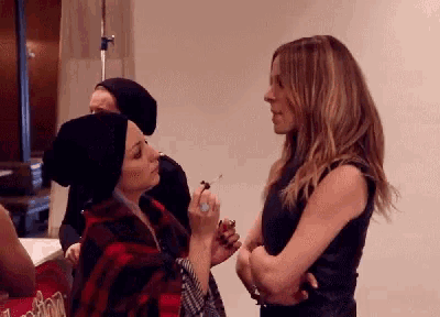 two women are standing next to each other in a room with a sign that says london on it
