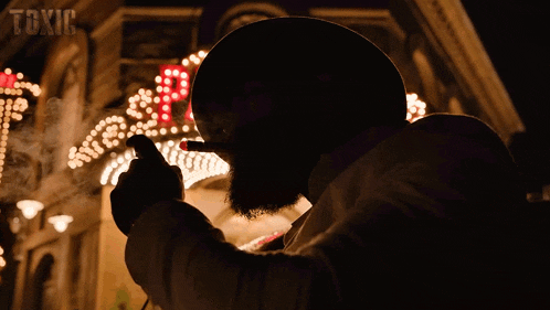 a man is smoking a cigar in front of a sign that says " toxic "