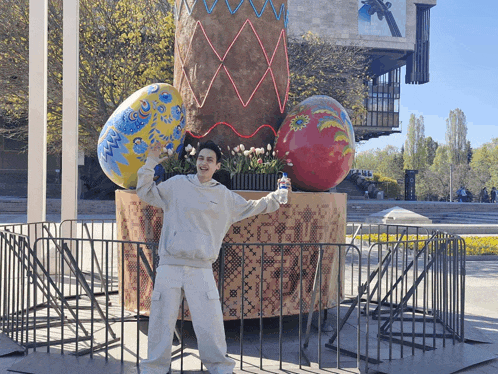 a man standing in front of a large easter egg