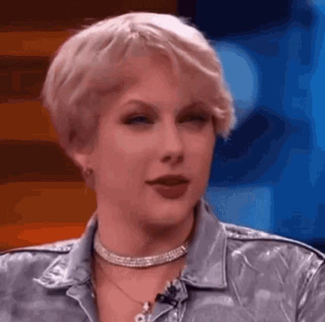taylor swift is wearing a silver jacket and a choker while talking on a show .
