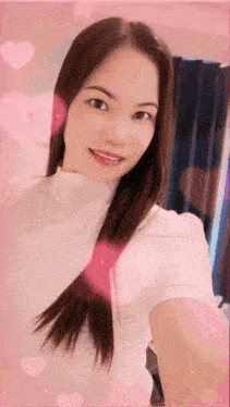 a woman in a white shirt is taking a selfie with pink hearts in the background