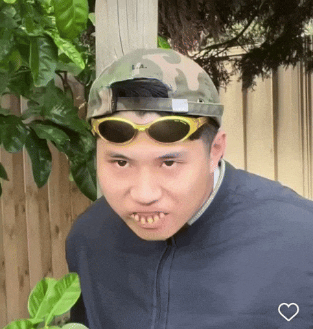 a man wearing sunglasses and a camo hat has a heart on his chest