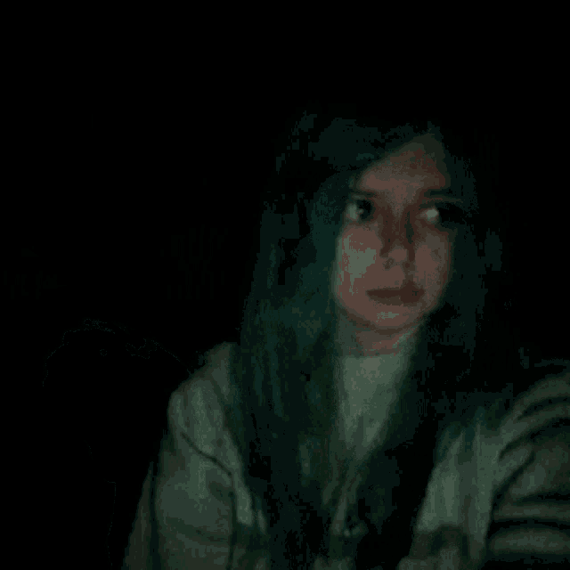 a girl with blue hair and green hair is smiling in the dark