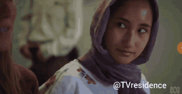 a woman wearing a purple scarf and a white shirt with the words @tvresidence on the bottom