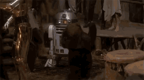 a group of people are standing around a r2d2 robot in a scene from star wars .