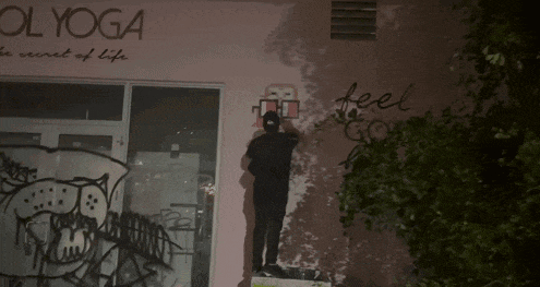 a man is standing on a ledge in front of a building that says feel