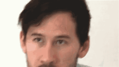 a close up of a man 's face with a beard against a white wall .