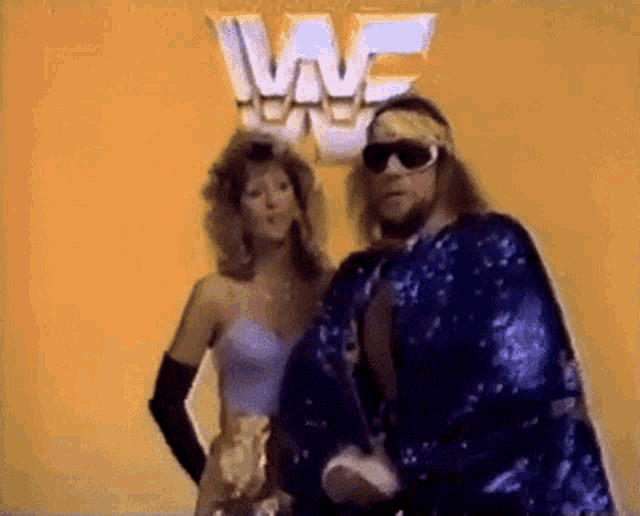 a man and a woman are standing next to each other in front of a sign that says wwe .
