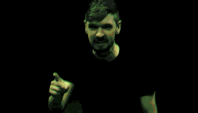 a man with a beard and a tattoo on his arm is holding his head in a dark room .
