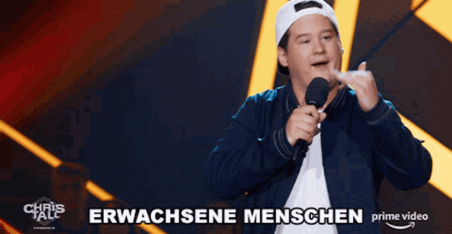 a man holding a microphone in front of a sign that says erwachsene menschen on it