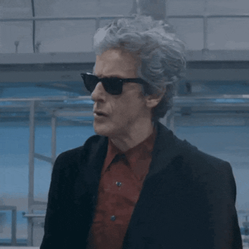 a man wearing sunglasses and a red shirt is standing in a room