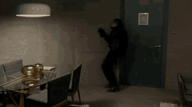 a man in a black suit is standing in front of a door in a dark room