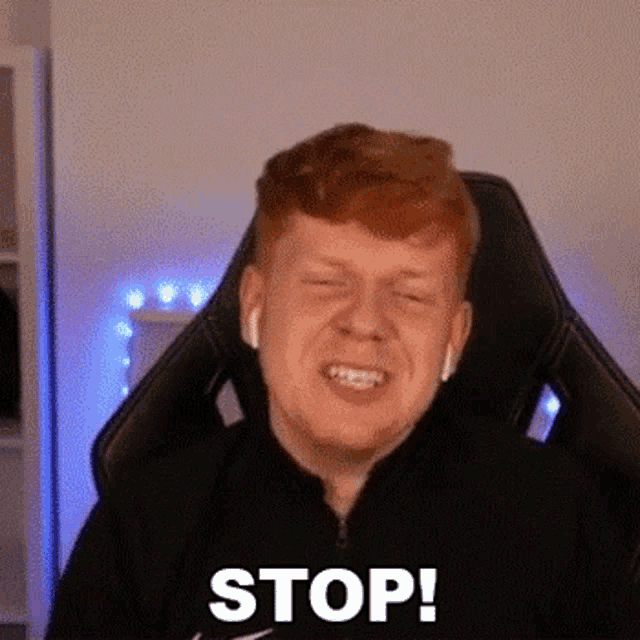 a man with red hair is sitting in a gaming chair with his eyes closed and making a funny face .