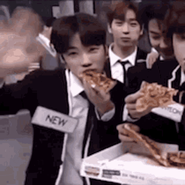 a group of young men are eating pizza together and one of them has a name tag that says new .