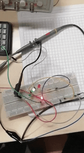 a calculator sits on a table next to a breadboard with wires attached to it