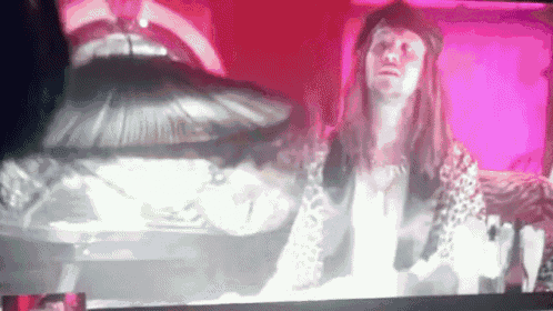 a woman in a leopard print shirt is sitting in front of a coffin on a television screen .