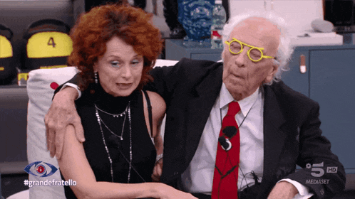 a man in a suit and tie is hugging a woman with red hair