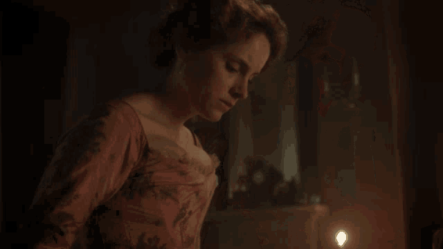 a woman in a pink dress is standing in front of a fireplace