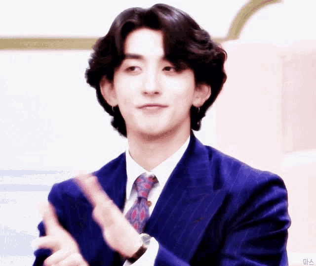 a man in a blue suit and tie is clapping