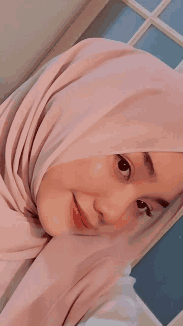 a woman wearing a pink hijab is looking at the camera