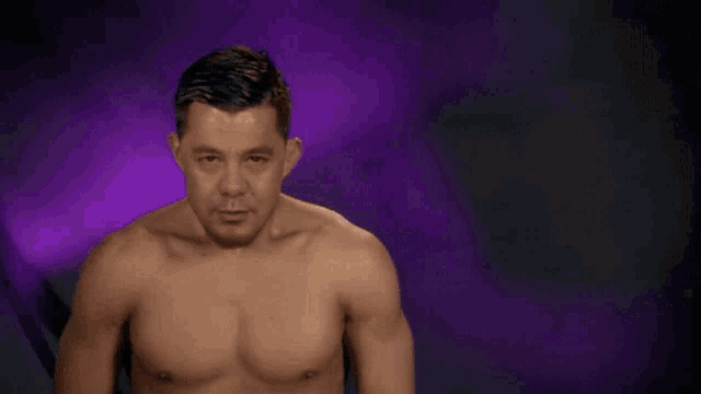 a shirtless man with a beard is smiling and looking at the camera on a purple background .