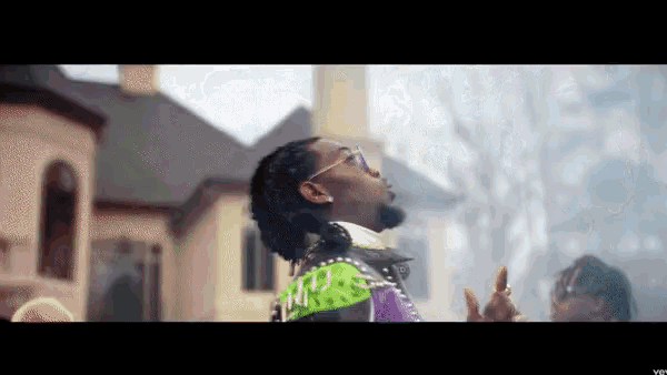 a man wearing sunglasses stands in front of a large building
