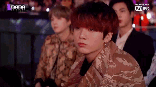 a man with red hair is sitting in a crowd of people at a concert .
