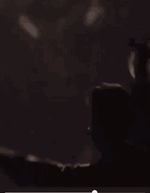 a man in a dark room with his arms in the air .