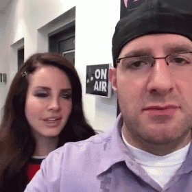 a man and a woman are standing next to each other in front of a sign that says on air